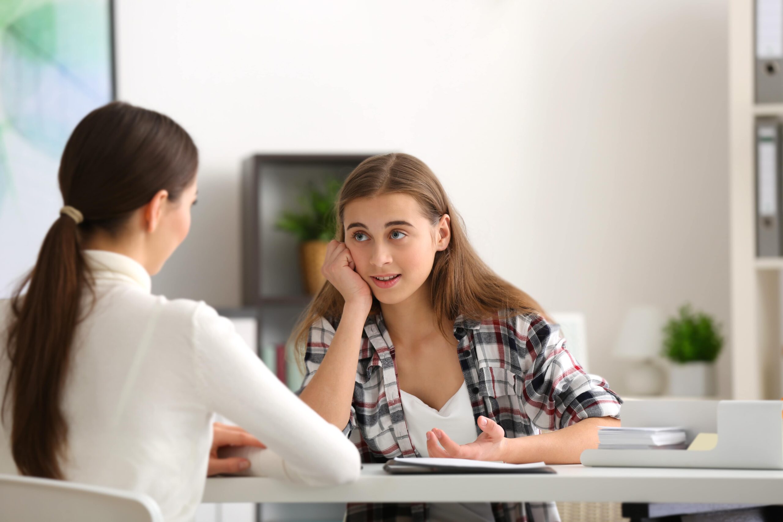 A teen speaking with a counselor at a table