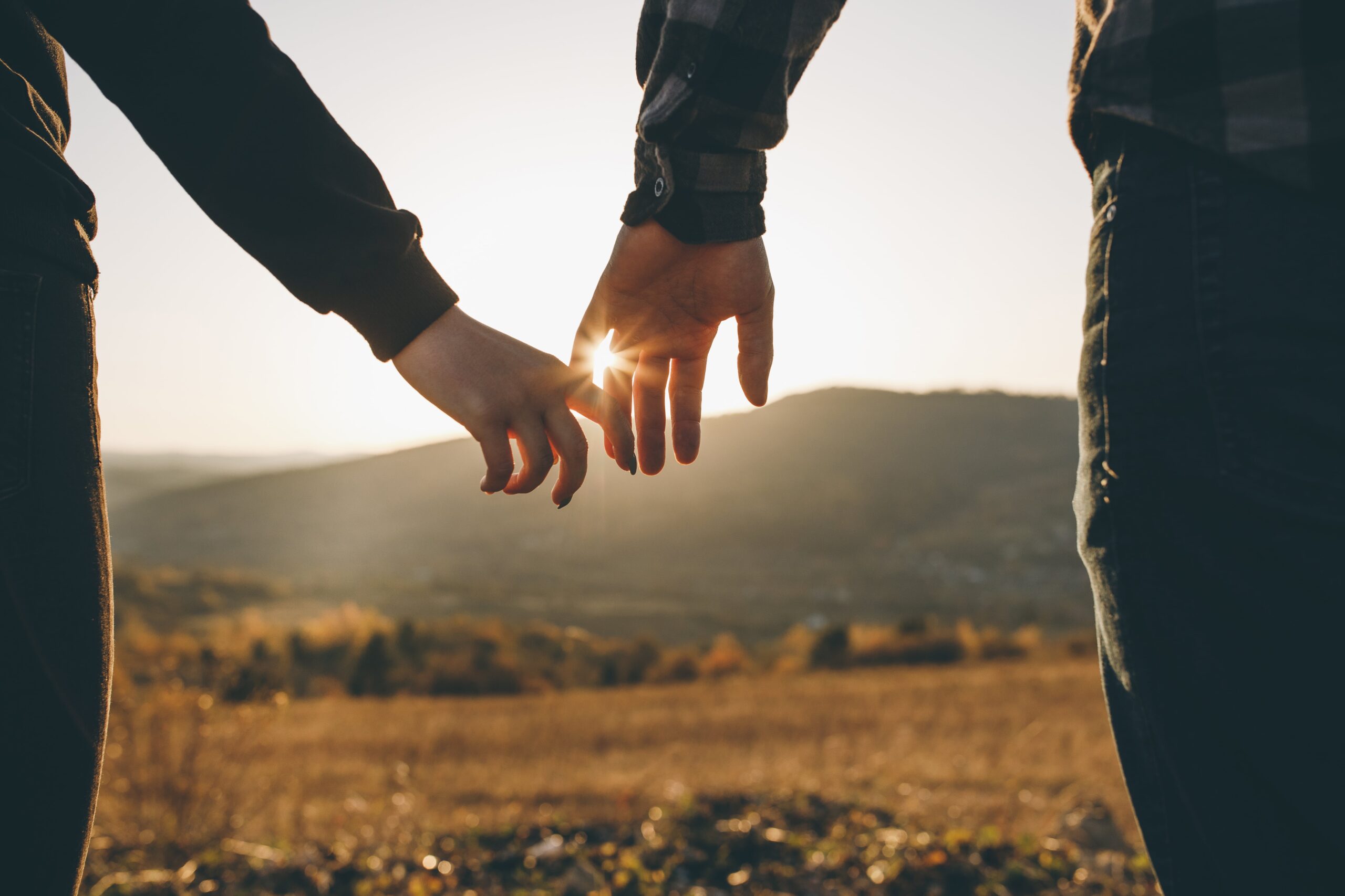 A couple reaching for each other in warm evening light