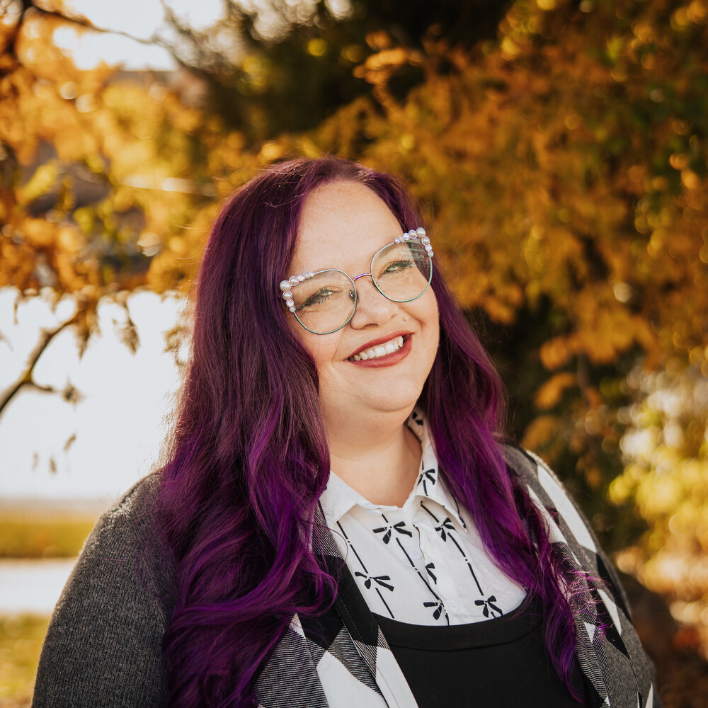 Alexis smiling outdoors in a gray cardigan