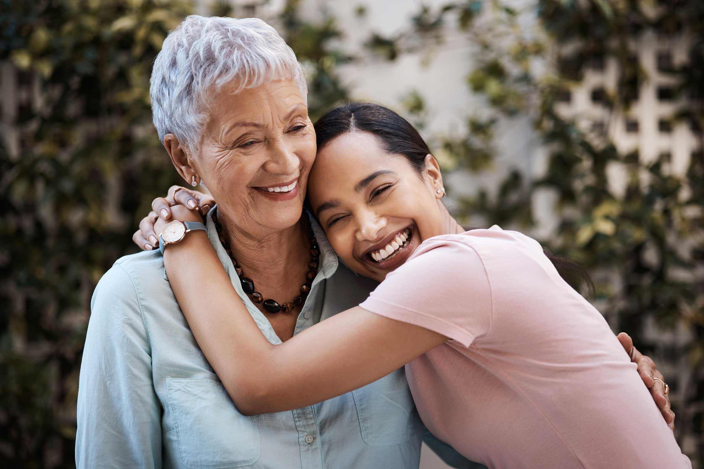 A younger woman hugging an elderly woman affectionately.