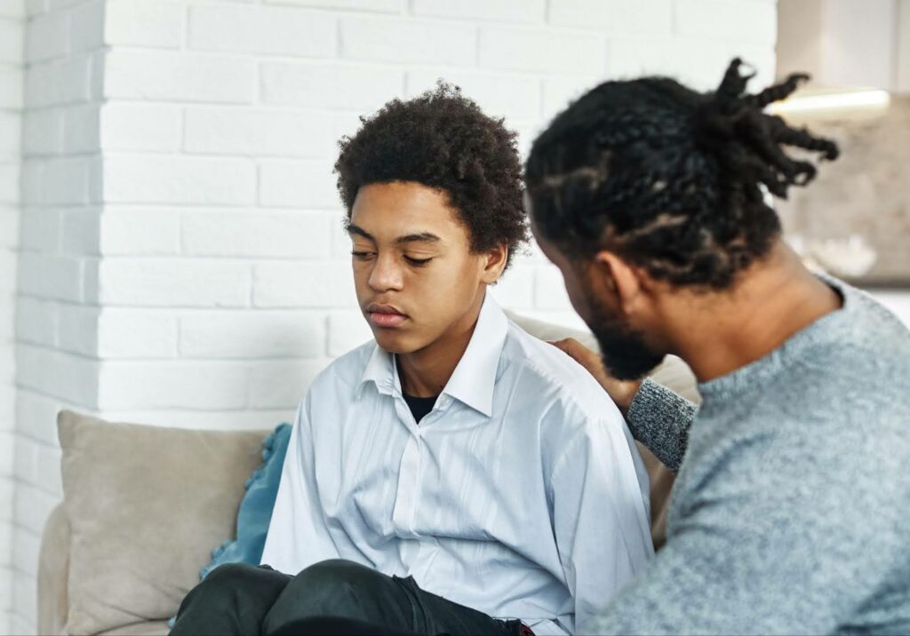 A man and a boy engaged in a counseling session while sitting on a couch.