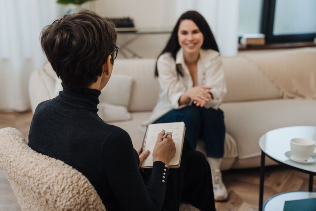 Two women engaged in individual counseling services on a couch, discussing personal growth and personal counseling.